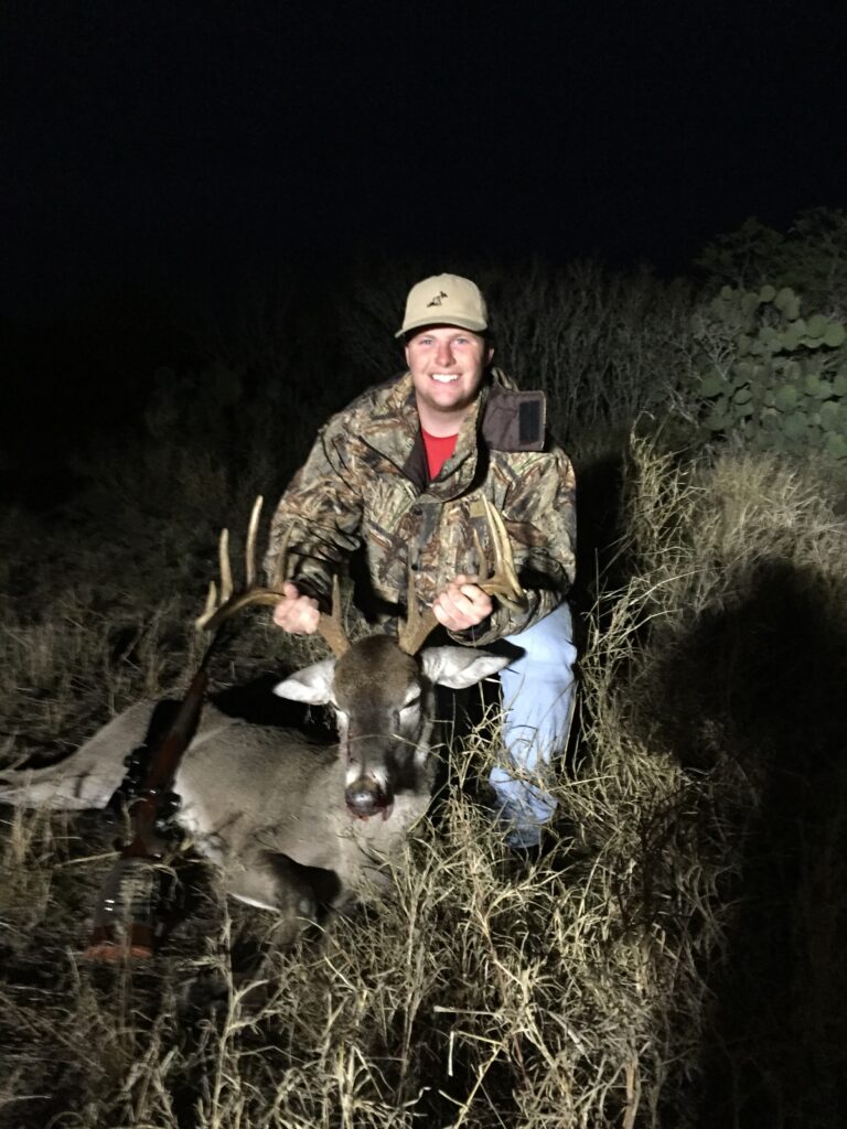 Man kneeling with a large deer he hunted at night.