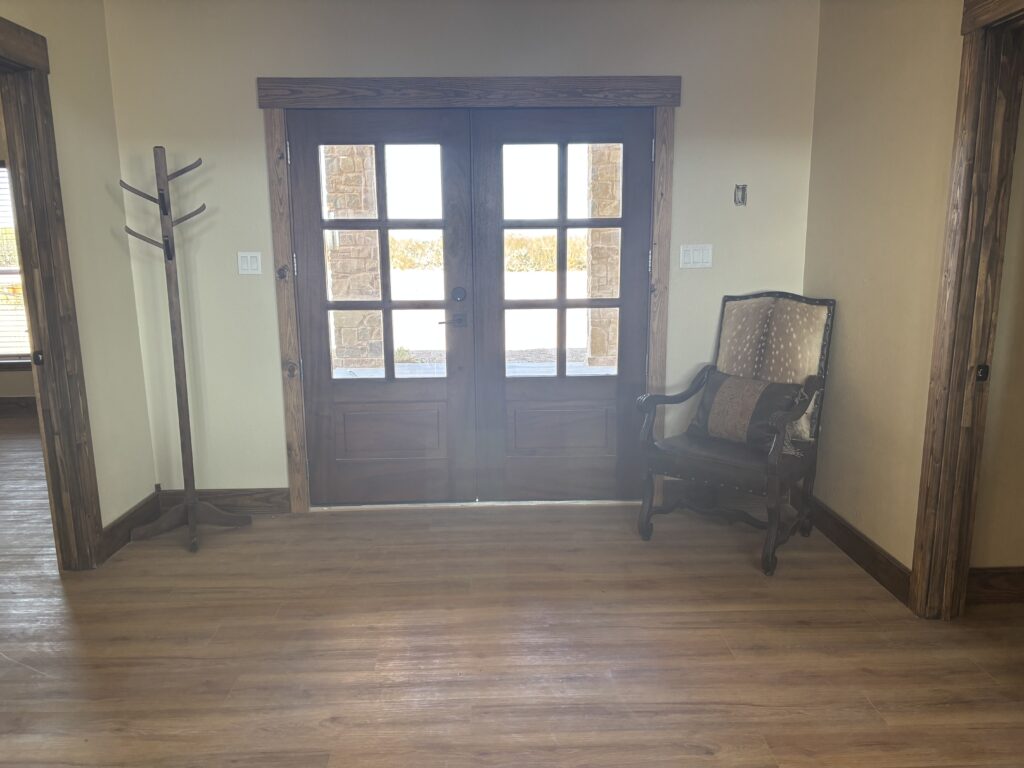 A wooden double door with window panes in a room with hardwood floors.