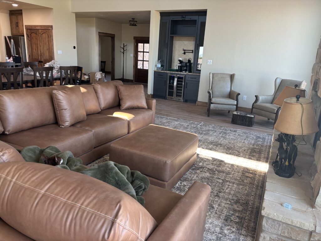 Spacious living room with brown leather furniture and a patterned rug.
